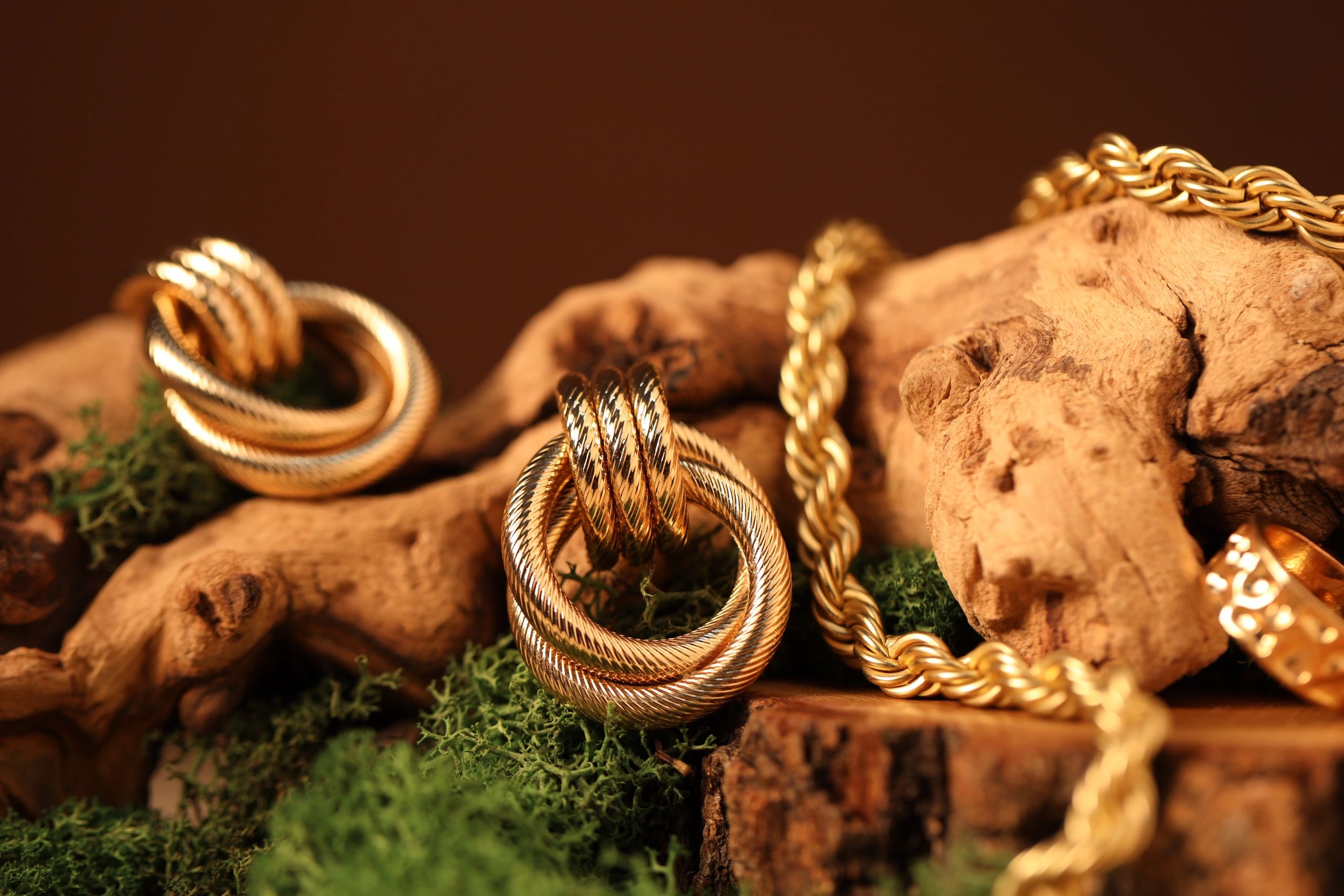 Closeup of modern gold jewelry styled on a textured surface